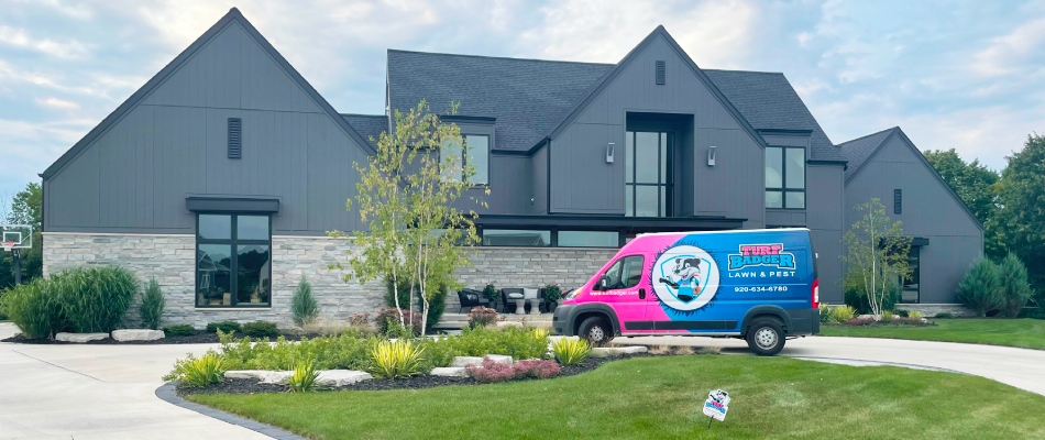 Turf badger work van parked in front of landscape bed and mowed lawn in Escanaba, MI.